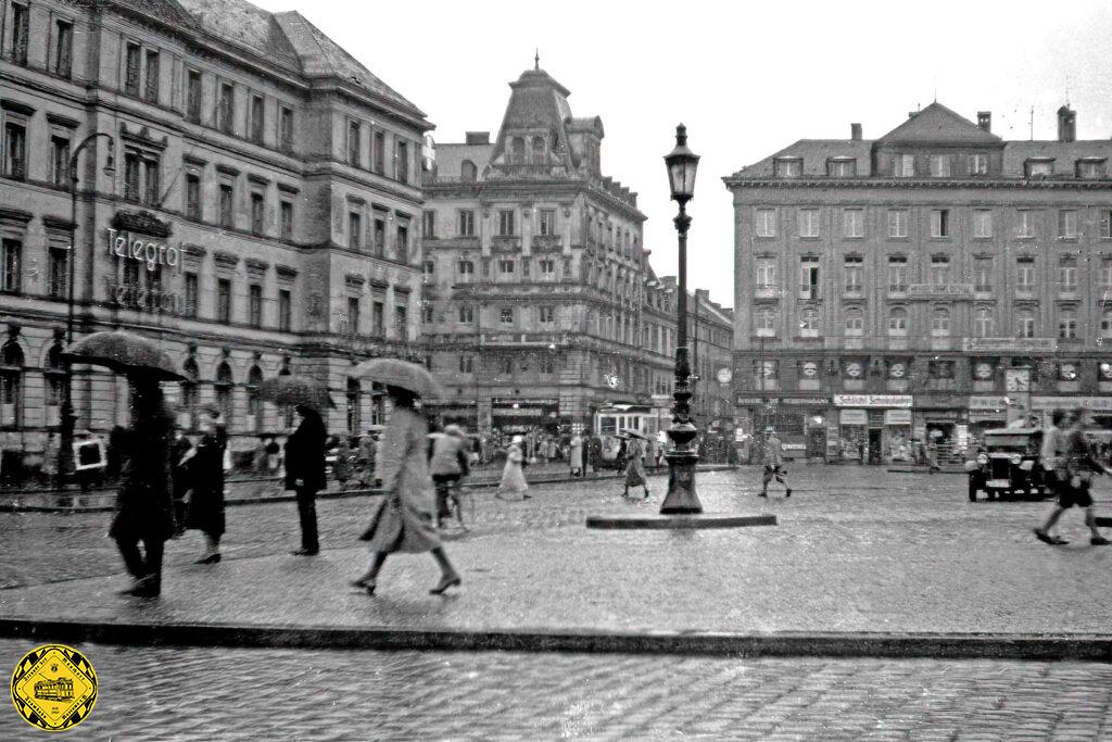 Das letzte Bild des intakten Bahnhofsgebäudes, dafür das erste Farbfoto von vor dem 2. Weltkrieg. Die großen Flaggen und martialischen Zusatzsäulen verheißen nichts Gutes.