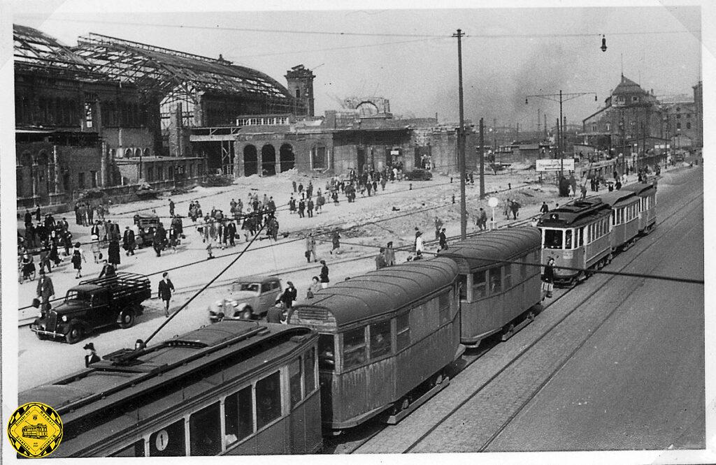 Das blieb übrig vom Münchner Hauptbahnhof. Die Trambahn fährt wieder mit Kriegswagen ohne Blechverkleidung und oft ohne Fenster und ein Gleis der Bockerlbahn und Schuttbahn führt über den Vorplatz des Hauptbahnhof, vor dem größtenteils zerstörten Bahnhof stehen hauptsächlich amerikanische Militärfahrzeuge.