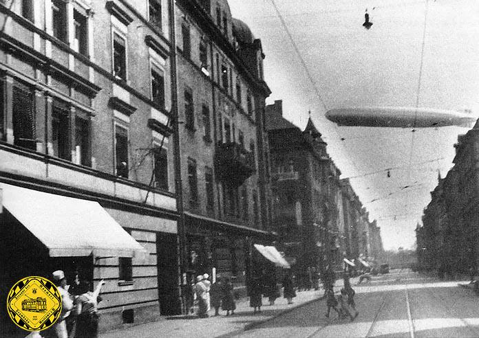 Attraktion 1908 am Himmel über der Görresstraße: hinter der Trambahn-Oberleitung fliegt ein Zeppelin über Schwabing.