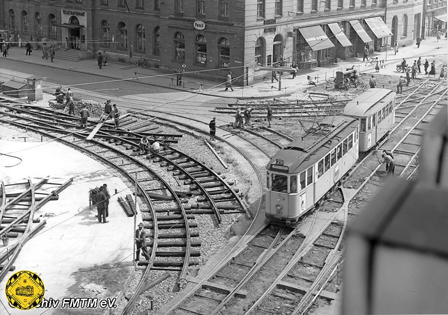 Am 24.6.1955 passiert der E-Triebwagen 583 an der Kreuzung Bayer- /Schillerstraße auswärts die Baustelle. Deutlich sieht man die neue Lage der Schienen mehr zur Mitte des Bahnhofplatzes.