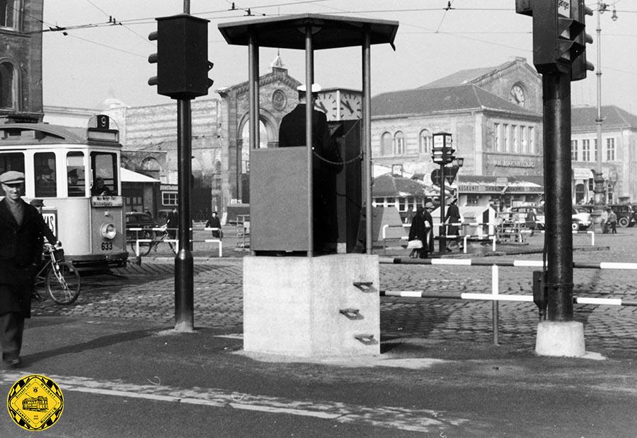Der Verkehr, vor allem der Autoverkehr, hatte auf dem Bahnhofsplatz nach dem Krieg so stark zugenommen, dass man im September 1950 eine erste Lichtsignalregelung für den Trambahnverkehr und den Autoverkehr schuf. Inzwischen gab es auch einen Verkehrspolizisten auf einem erhöhten Podest, wie er zu dieser Zeit an manch anderen Plätzen der Stadt eingesetzt wurde: Sendlingertorplatz, Marienplatz Stachus und so weiter.