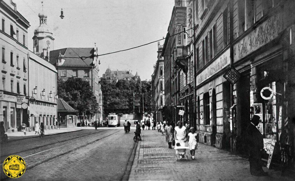 Ein sehr interessanten Bild mit einer Menge Zeitgeschichte. Der Blick geht durch die Humboldtstraße über die Kreuzung mit der Pilgersheimerstraße zum Kolumbusplatz. Links sehen wir das Haus, das von 1926–1967 das Kino Primus-Palast war. Anschließend zog dort der Sicherheitsdienst ZSD Carl Wiedmeier GmbH („Schwarze Sheriffs“) ein und zuletzt dann eine Balettschule. Im Erdgeschoß befindet sich heute ein Supermarkt. Anschließend dahinter die Humboldt-Schule mit Turm, die in den Jahren 1895 bis 1897 nach Plänen von Karl Hocheder gebaut wurde. Im Krieg wurde diese Schule zerstört und nicht wieder aufgebaut, sondern 1951 abgetragen. 