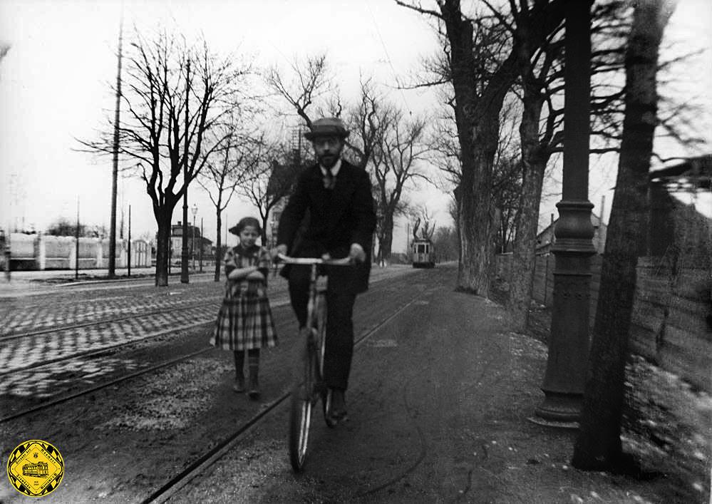 Vermutlich galt der Augenmerk dieses Bildes dem Radfahrer: ein Trambahnzug im Hintergrund unterwegs 1912, Aufnahmeort ist auf der Höhe der Johann-Fichte-Straße stadtauswärts.