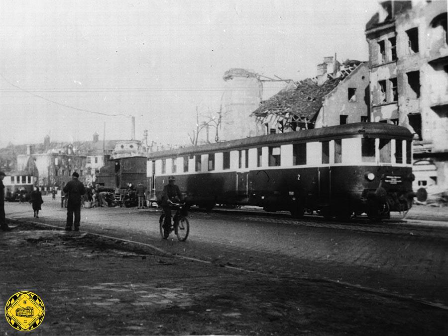 Dampflokomotiven und einen Reichsbahn-Steuerwagen der von der Reichsbahn betriebenen Hilfsbahn Linie IV vom Stiglmaierplatz kommend, die hier am Anwesen 158 der Nymphenburgerstraße ihr Kohlelager hatten. 