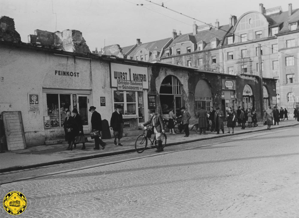 Im Westteil des Rorkreuzplatzes im April 1951 sind Läden in die Erdgeschoße der ausgebomten Ruinen eingezogen: heute steht hier der Kaufhof am Rotkreuzplatz.