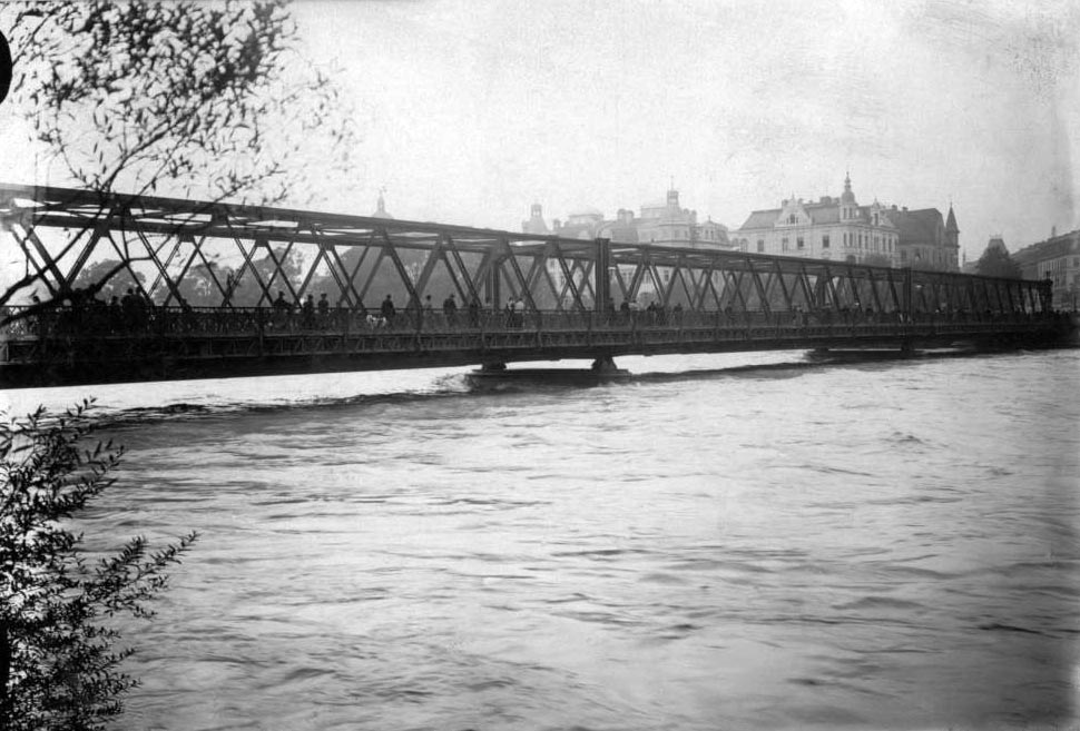 Die Wittelsbacher Brücke war einer der wenigen Brücken, die dem großen Hochwasser 1899 widerstanden. Viele Schaulustige tummelten sich bei diesem Spektakel auf der Brücke. Im Hintergrund der Baldeplatz.