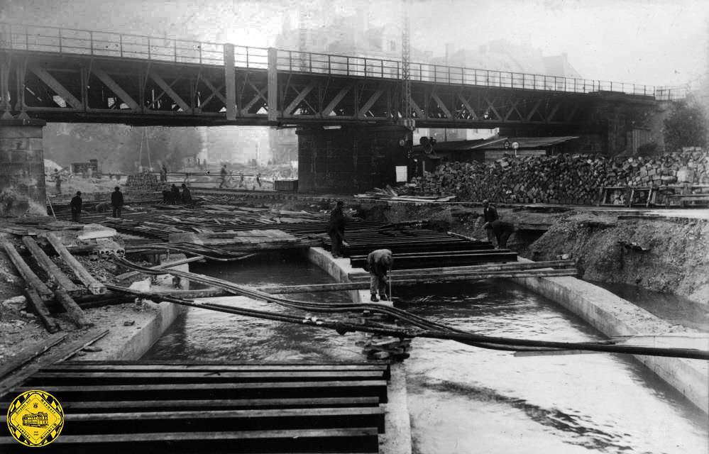 Das Jahr 1941 machte am Kolumbusplatz eine Regulierung des Auer Mühlbaches nötig. Das erinnert an die erste Funktion der Brücke 1871, den Auer Mühlbach zu überbrücken. Aber seit dem ist den Mühlbach viel Wasser hinunter geflossen.