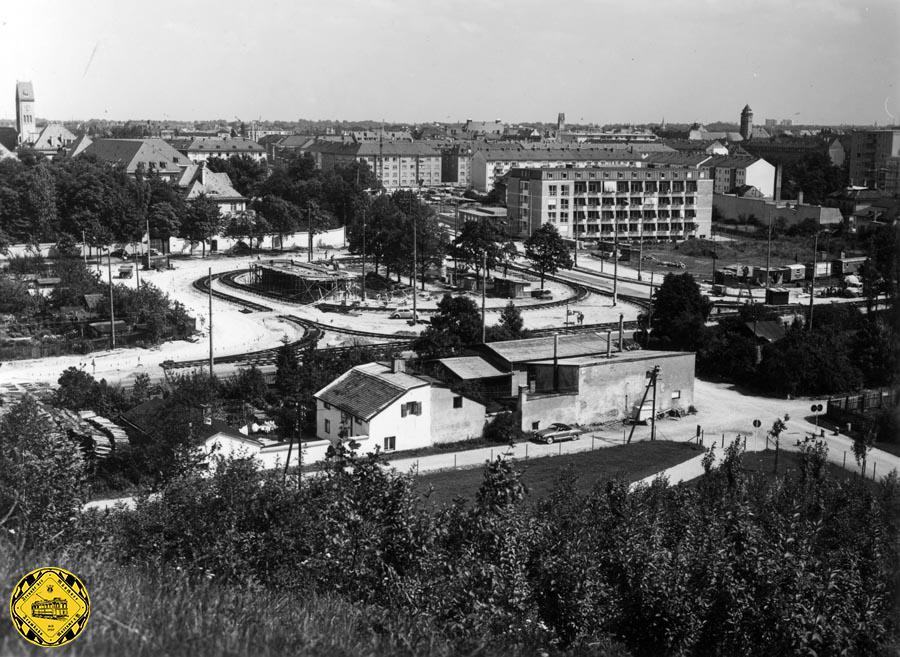 Blick vom Schuttberg am Luitpoldpark auf die Baustelle der ersten Schleife am Scheidplatz am 7. August 1959. Auch das neue Stationshaus auf dem Scheidplatz ist in Bau.