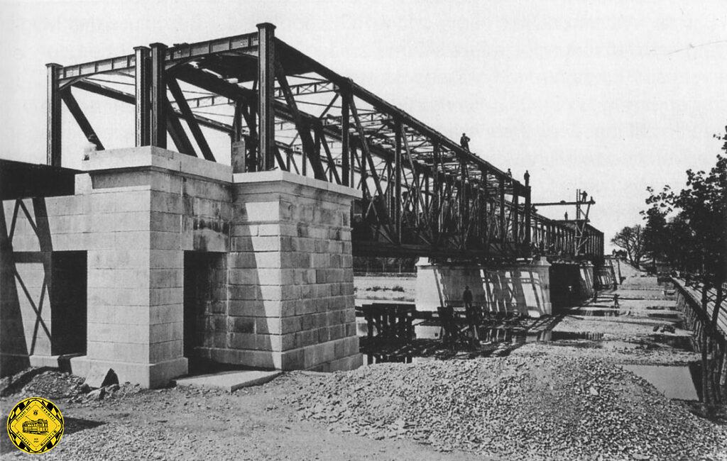 Das Bild von 1870 zeigt die Braunauer Eisenbahnbrücke kurz vor der Fertigstellung. Die Zufahrt zur Braunauer Eisenbahnbrücke im Rahmen des Südrings kam von Osten durch den Graben bei der Regerbrücke und Nockherberg-Brücke und ging in einem sanften Bogen über die Mühlbachbrücke und Brücke an der Pilgersheimerstraße und der gemauerten Durchfahrt an der Claude-Lorrain-Straße zur Braunauer Brücke. Von dort musste nach einer kleinen Insel der große Stadtbach und die daneben führende Staubstraße überquert werden. Da die Strecke in Brückenhöhe ankam, wurde an der Staubstraße sofort beim Bau eine Brücke eingezogen anders wie an der Thalkirchnerstraße oder Lindwurmstraße, wo einfache Bahnübergänge waren.