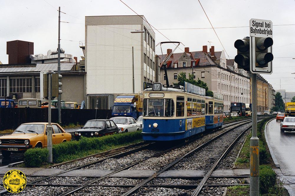 Am 26.Mai 1983 kommt der TW 2609 stadtauswärts an der Industriegleis-Kreuzung der Firma Meiller vorbei. Damals war das Gleis schon nicht mehr regelmäßig genutzt. Man sieht die Ampelanlage, die den Kreuzungsverkehr damals regelte.