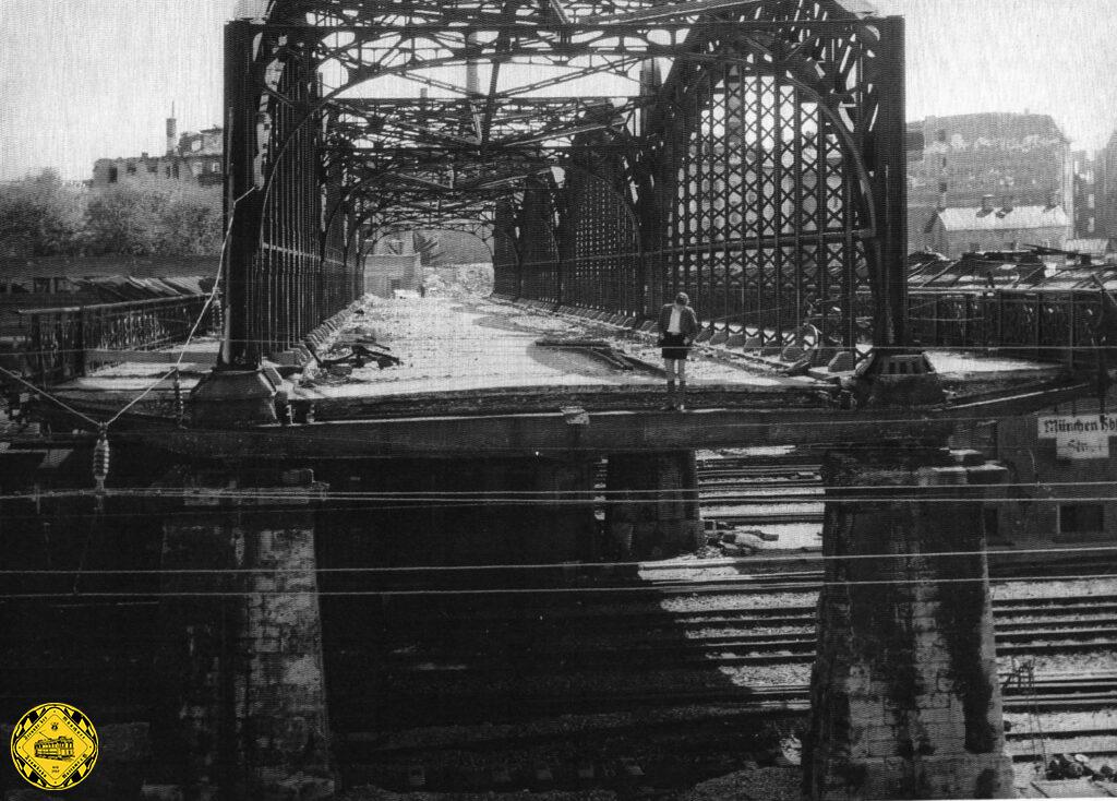 Auf der Brücke kann man noch die verbliebenen Schmalspurschienen der Schuttbahn sehen. Die Oberleitung der Reichsbahn ist notdürftig an den verbliebenen Trägern der beschädigten Brücke befestigt. 