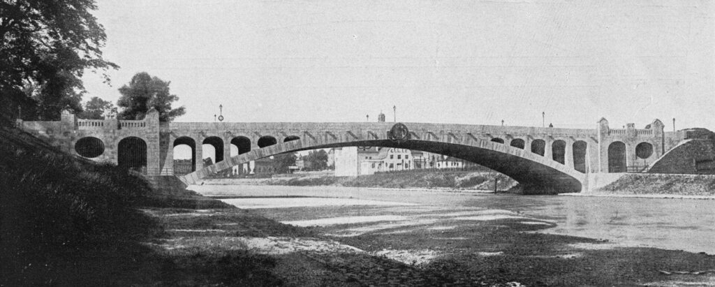 Die Max-Joseph-Brücke von Norden gesehen mit dem Gebäude des Turnvereins am Isarufer damals.