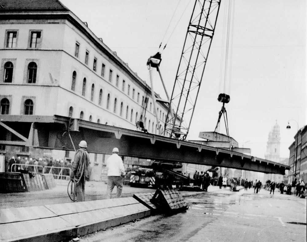 1966 11 20 Stahlhochbrücke Von Der Tann Str Ludwigstraße Die ersten Brückenelemente für den Mittelteil sind 30m lang und 55 Tonnen schwer. Danach werden mit einem zweiten Autokran die weiteren Brückenelemente in beide Richtungen bis zu den Rampen eingesetzt. Am Abend des 19.November 1966 sind dies Arbeiten komplett abgeschlossen. 