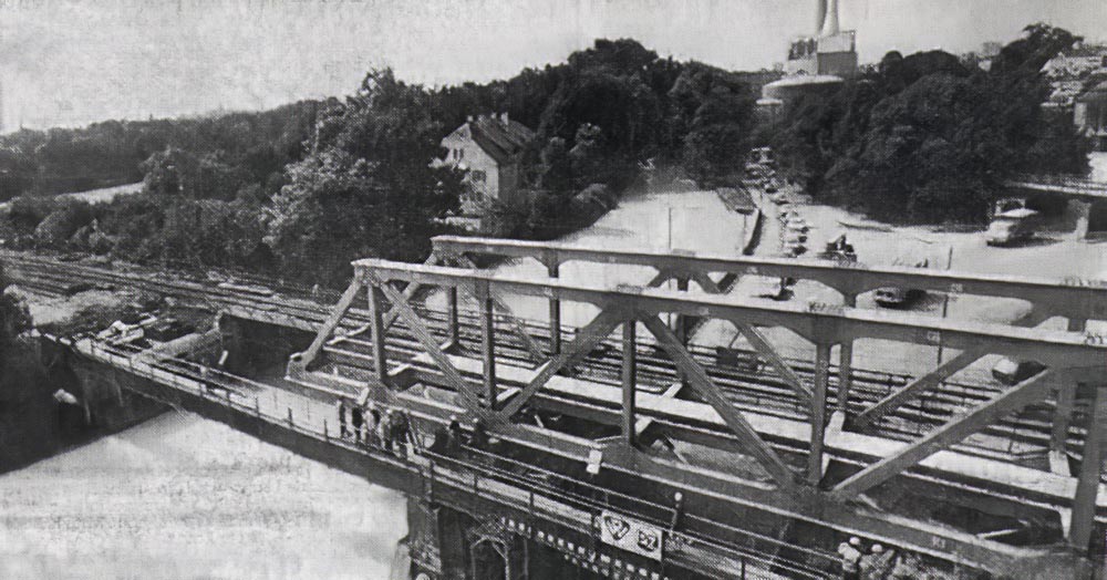 Am 23.September 1981 wurde die alte Brücke über die Isartalstraße ersetzt.

Mit einem Seil wurde die 55 Tonnen schwere Behelfsbrücke über die Isartalstraße und den großen Stadtbach gezogen, während auf dem anderen südlichen Gleis der Bahnbetrieb ungestört weiterlief.