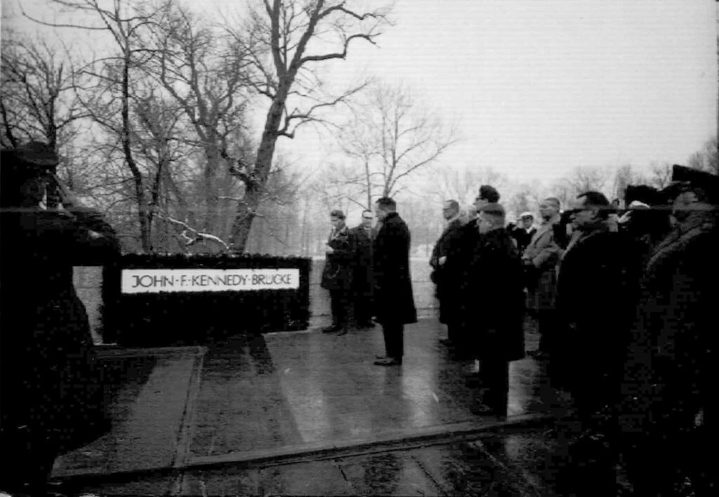 Bei der Einweihung der Kennedybrücke am 18.Dezember 1963 waren neben dem Oberbürgermeister und Stadträten auch Militärs der Amerikanischen Armee und der Generalkonsul und der Bauminister Seebohm anwesend. Da die Namensgebung sehr kurzfristig geändert wurde, war das heute an der Brücke angebrachte Bronze-Schild nicht fertig geworden. 