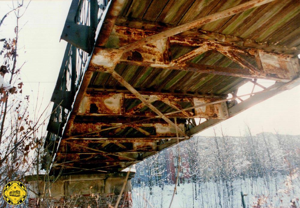 Wir sind im Jahr 1991. Romantiker und Gutachter unterscheiden sich grundlegend bei der Wahrnehmung von Dingen. Der eine sieht eine wundervolle historische alte Brücke, der Gutachter dokumentiert vor allem eines: ein hoher Arbeitsaufwand, um diese Brücke von Grund auf zu sanieren. Die Holzbohlen wurden zwar öfter schon gewechselt, aber der Unterbau ist rostig und das Mauerwerk stark angegriffen.